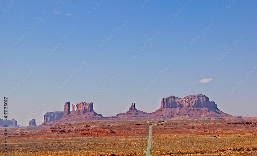 Long Road Leading To Outcropping Mountains In Monument Valley, Utah Long Road Leading To Outcropping Mountains In Monument Valley, Utah