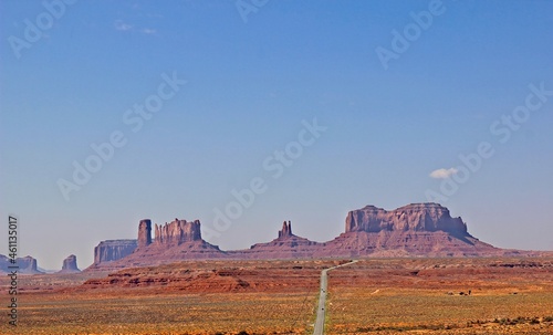 Long Road Leading To Outcropping Mountains In Monument Valley, Utah