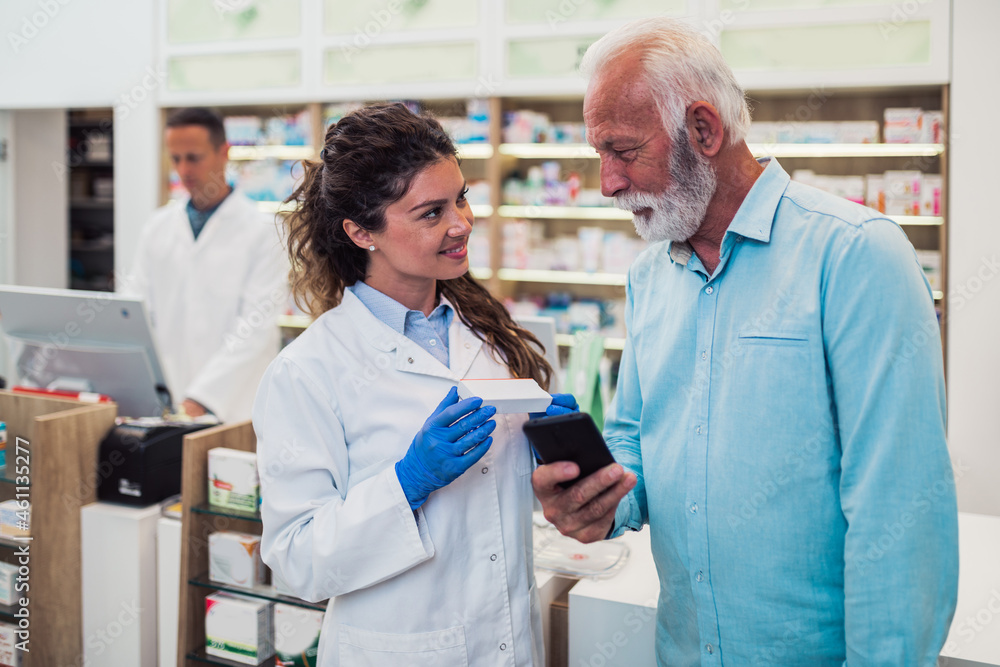 Fototapeta premium Professional pharmacist talking with senior customer in modern drugstore.