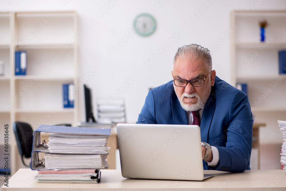 Old male employee unhappy with excessive work in the office Old male employee unhappy with excessive work in the office