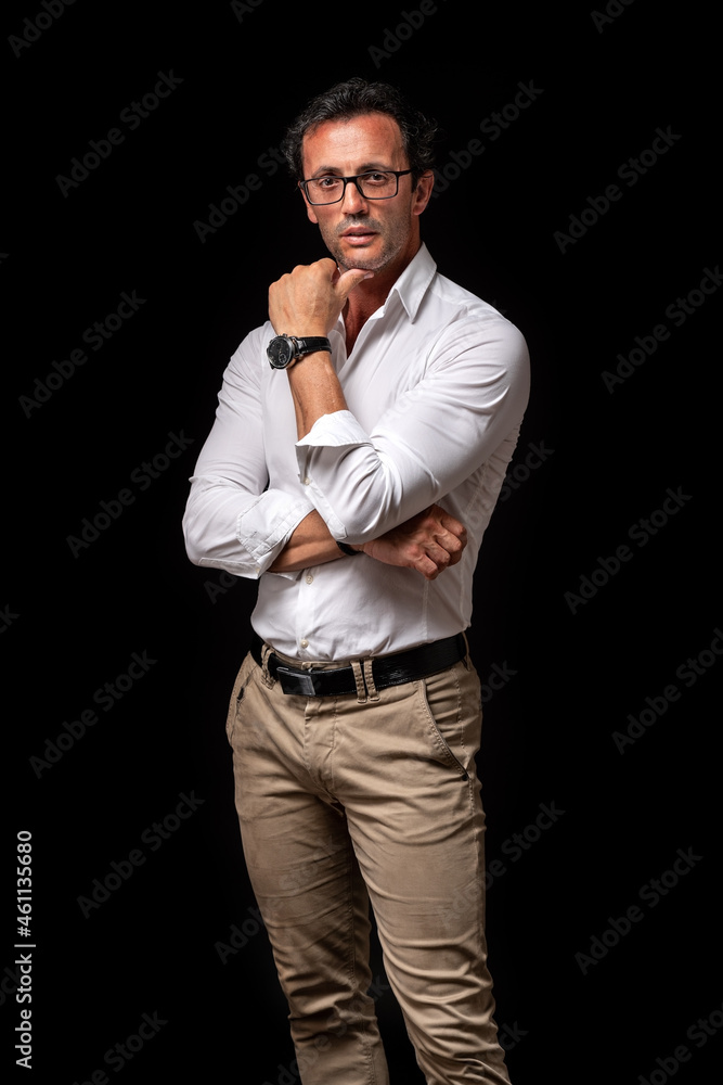 Portrait of serious caucasian man with crossed arms, wearing watch and casual denim shirt, isolated on black background