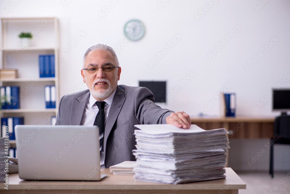 Old male employee unhappy with excessive work in the office Old male employee unhappy with excessive work in the office