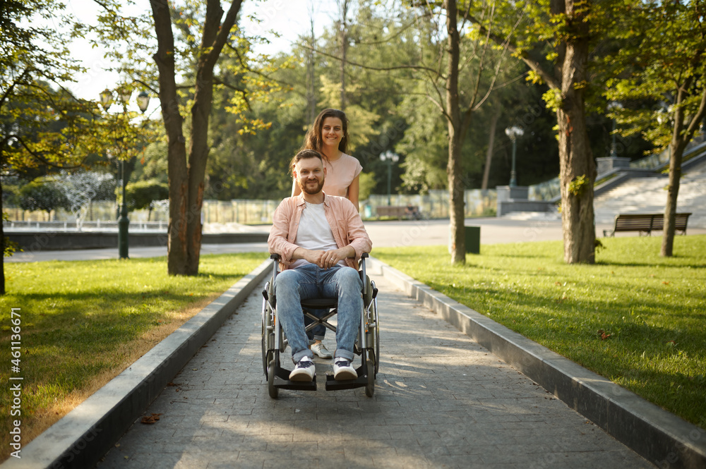 Young couple with wheelchair walking in the park