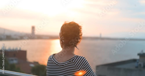 Rich retired happy woman is watching sea on her beautiful landsace balcony. Sunlight and flare in afternoon time. Happy retired senior photo