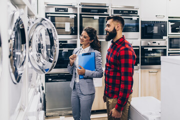 Young man buying washing machine in appliances store.