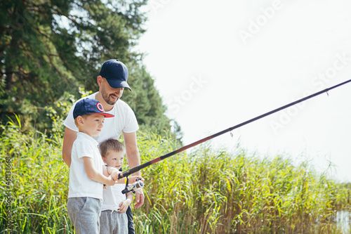 A father with two young sons fishes on the lake in the summer on weekends