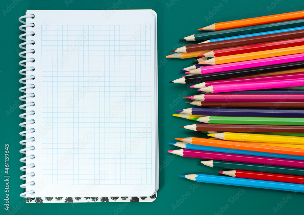 Multicolored pencils and a notebook on the table Multicolored pencils and a notebook on the table