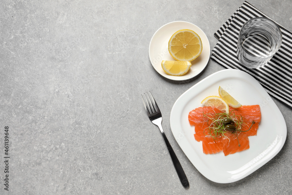 Salmon carpaccio with capers, microgreens and lemon served on grey table, flat lay. Space for text Salmon carpaccio with capers, microgreens and lemon served on grey table, flat lay. Space for text