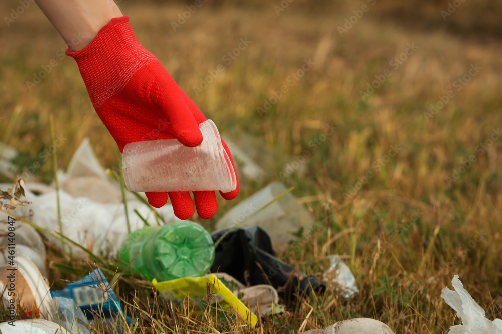 Fototapeta premium Woman in gloves collecting garbage in nature, closeup