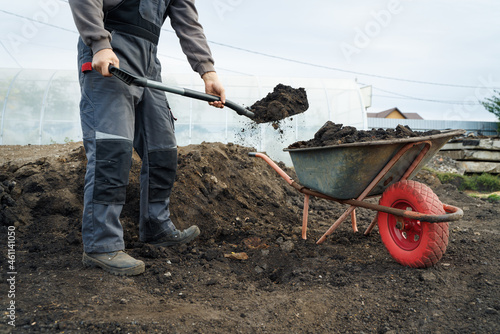 Working with garden tools, shovel and wheelbarrow on the site of a country house. Preparation for construction work.