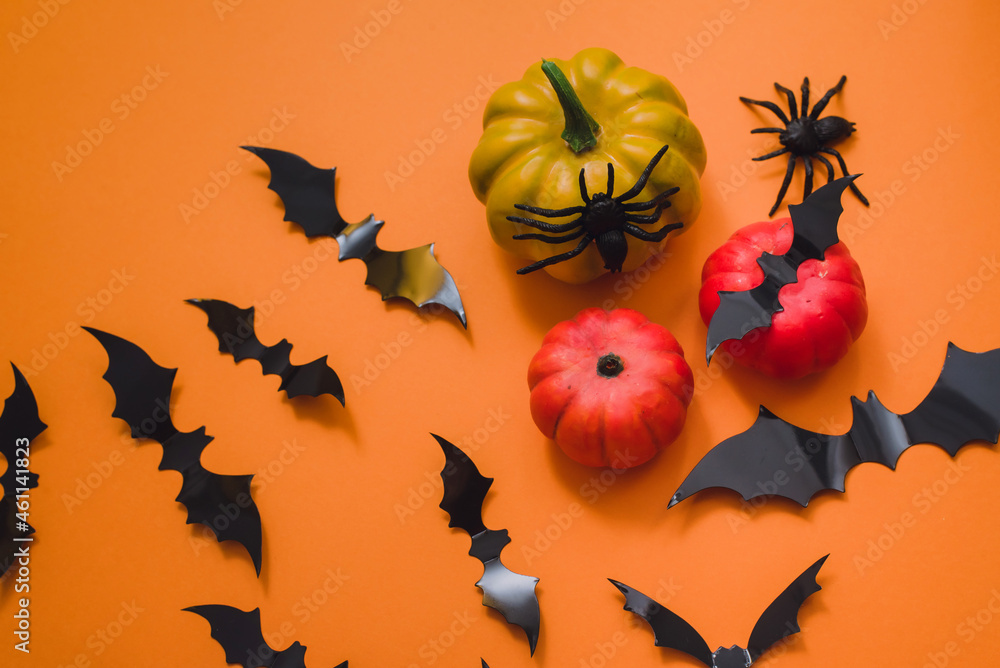 Happy halloween holiday. Halloween decorations, bats, spiders, pumpkins on an orange background. Flat lay, top view Happy halloween holiday. Halloween decorations, bats, spiders, pumpkins on an orange background. Flat lay, top view