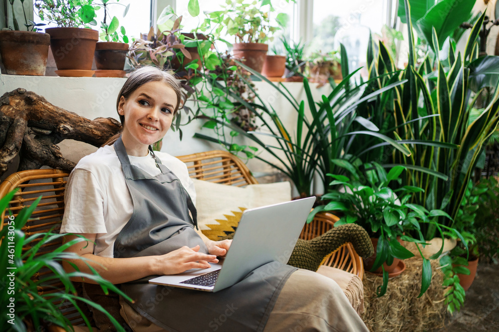 Shop for home plants. A woman sells flowers to a small business. Employee surf the internet information browser.The florist works in the workshop. Shop for home plants. A woman sells flowers to a small business. Employee surf the internet information browser.The florist works in the workshop.