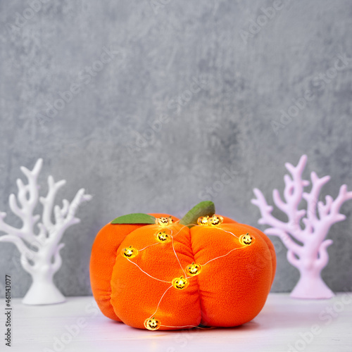 Halloween decoration toy plush pumpkin with a green tail and a garland of glowing pumpkins