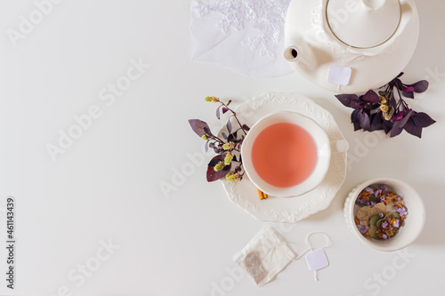 Cup of ginger tea composition with teapot  tea bag and purple leafs on white background. Flat lay  top view. 