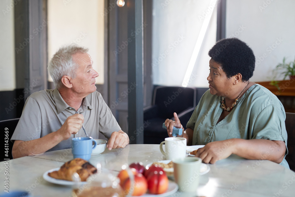 Side view portrait of two senior people enjoying breakfast at table in modern nursing home Side view portrait of two senior people enjoying breakfast at table in modern nursing home