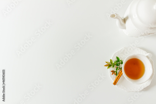 Cup of tea frame with tea pot and green leaves on white background. Flat lay, top view. 