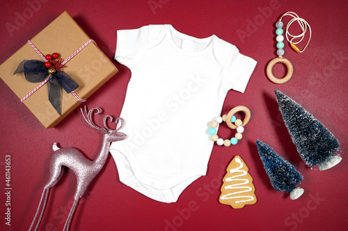 Baby onesie romper bodysuit product mockup. Christmas svg craft product mockup with pink reindeers, gift, gingerbread cookies and Xmas trees against a dark red magenta background.