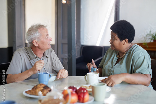 Side view portrait of two senior people enjoying breakfast at table in modern nursing home