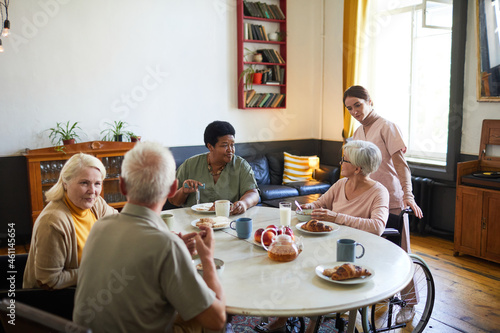 Fotografi Warm-toned portrait of diverse group of senior people enjoying breakfast in cozy