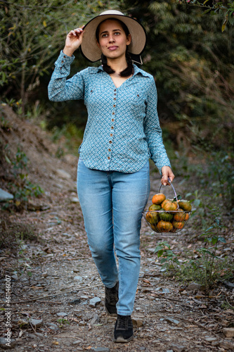 Latin woman, peasant. harvesting oranges. fruits of the field woman in the field. agricultural latina. fruit trees, field. in the path. happy. showing his harvest.