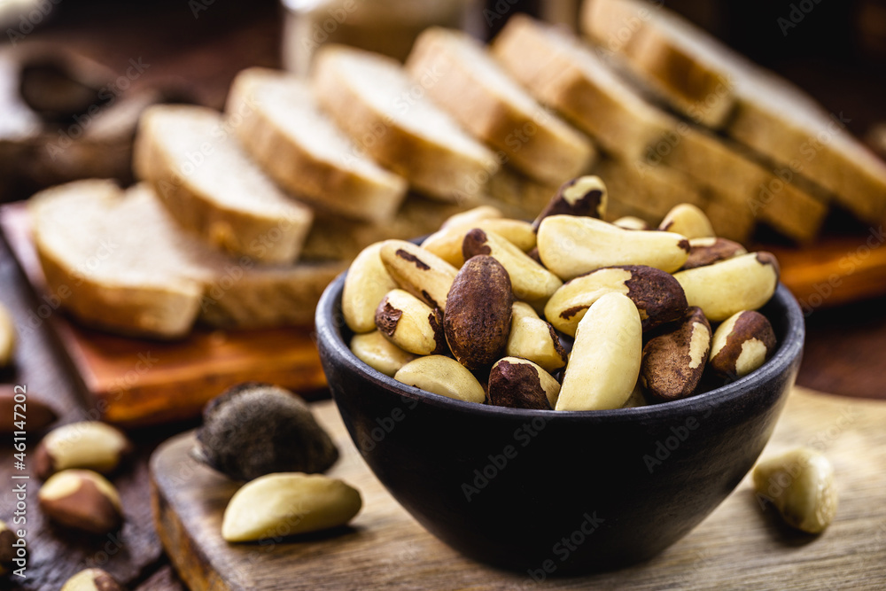 bowl of Brazil nuts with vegan whole grain bread in the background, healthy vegan cooking ingredient, exotic nut bowl of Brazil nuts with vegan whole grain bread in the background, healthy vegan cooking ingredient, exotic nut