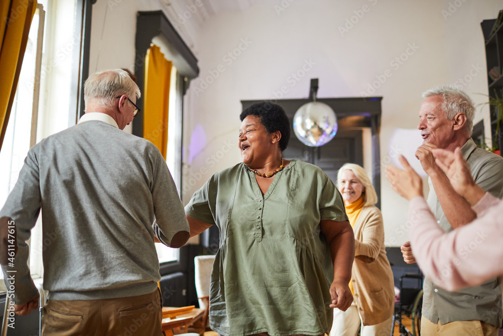© Seventyfour - Diverse group of smiling senior people dancing while enjoying activities in retirement home, copy space