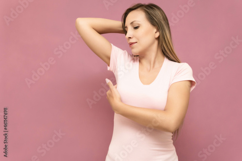 young woman does self-exam for breast cancer prevention wearing pink t-shirt and color background. High quality photo photo