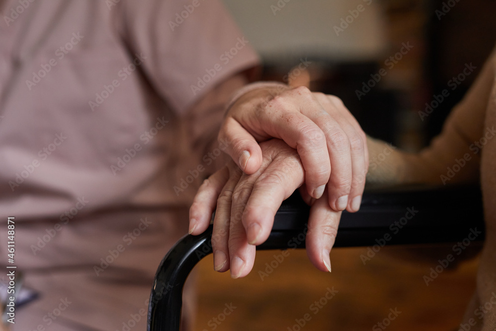 Fototapeta premium Close up of two senior people holding hands during therapy session in nursing home