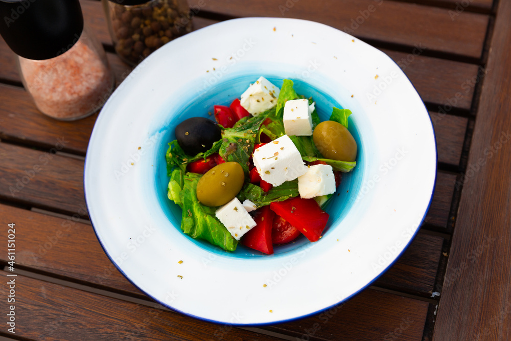 Greek salad with fresh vegetables and feta cheese on a ceramic plate in a restaurant