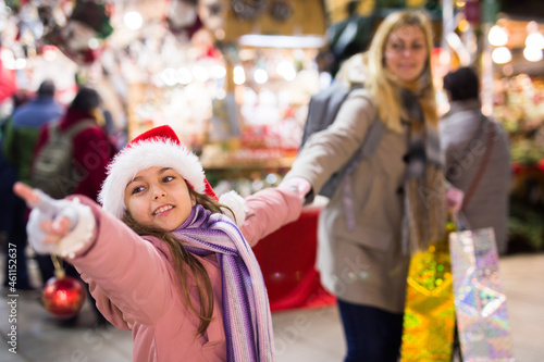 Young mother with her daughter shopping on outside Christmas market pointing to something © JackF