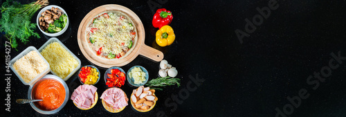 Food ingredients , Spices for cooking mushrooms, tomato sauce, cheese, sausage, bacon, bell pepper, ham, pineapple, parsley, broccoli and delicious pizza on black concrete background. View from above
