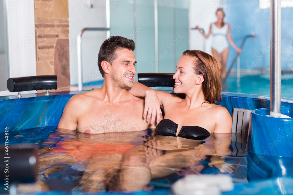 Couple is resting in a pool in time spa-day at the salon. Focus on both persons