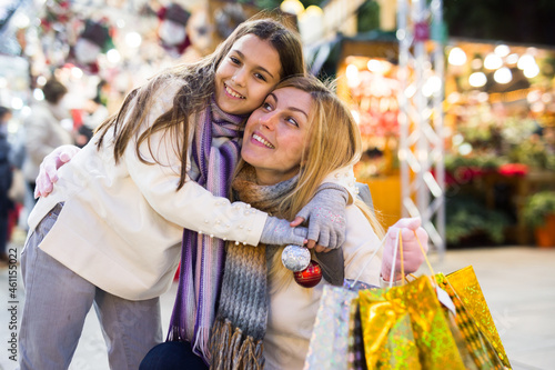 Portrait of happy family after shopping for gifts - daughter hugs mom at street market
