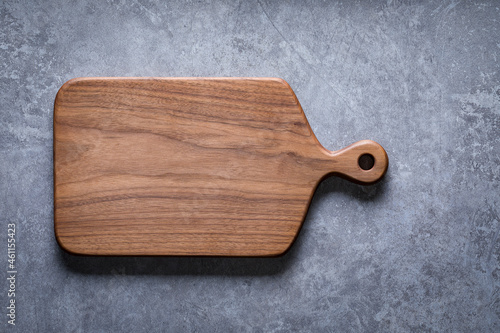 Handmade black walnut wooden cutting board on cement textured tabletop. Walnut wooden chopping board. Walnut chopping board background element.