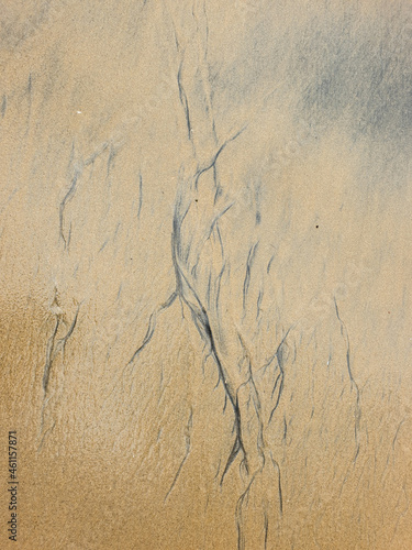 Patterns on the beach formed by the waves lapping the sand.