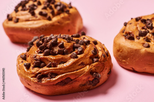 Close up of sweet roll breads with chocolate chips on pink background. Horizontal photo. Top view angle. Food and healthy concepts.