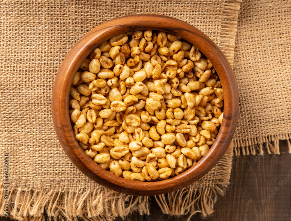 Wheat flakes cereal breakfast in wooden bowl with dry spikelets on the rustic background. Selective focus. Wheat flakes cereal breakfast in wooden bowl with dry spikelets on the rustic background. Selective focus.