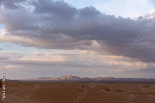Nature and landscapes of dasht e lut or sahara desert with sand dunes in foreground and cloudy evening sky and mountain in background