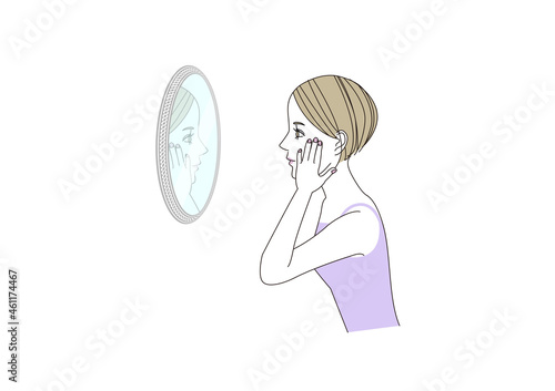 頬に手をあてて鏡をのぞき込んでいる女性　横顔