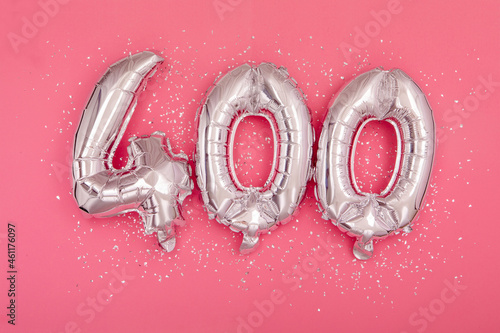 From above of silver shiny balloons demonstrating number 400 four hundred pink background with scattered glitter photo