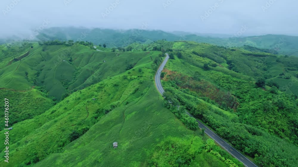 Aerial view of countryside road passing through the lush greenery and foliage tropical rain forest mountain landscape in the Northern Thailand, Nan province. Aerial view of countryside road passing through the lush greenery and foliage tropical rain forest mountain landscape in the Northern Thailand, Nan province.