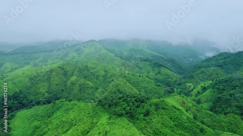 Aerial view drone shot of flowing fog waves on mountain tropical rainforest In the evening,Bird eye view image over the clouds Amazing nature background with clouds and mountain peaks.