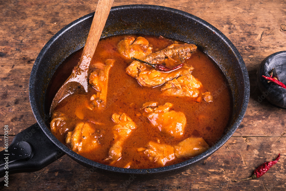 Stewed chicken with paprika, tomato sauce and hot pepper in a frying pan on the table, close-up Stewed chicken with paprika, tomato sauce and hot pepper in a frying pan on the table, close-up