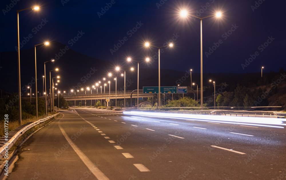 Highway car light trails at night - Asphalt highway and electric poles at night