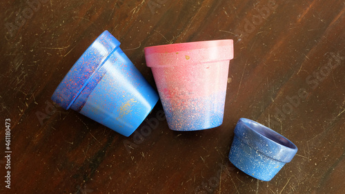 Colorful terracotta pots painted in blue and pink arylic paints. On a wooden surface.  photo