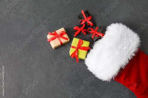 Christmas sock with coal and gift boxes on dark background
