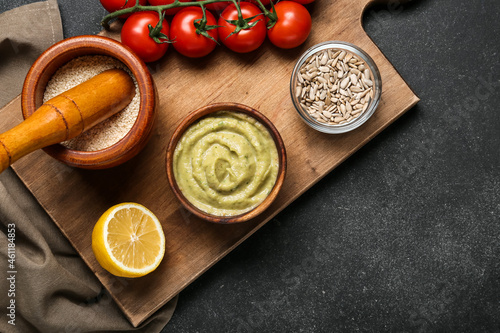 Bowl with tasty baba ghanoush, mortar and products on dark background