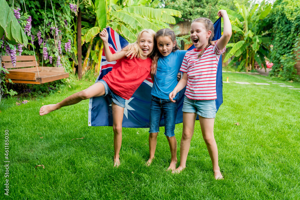 Fototapeta premium National day of Ausralia. Happy patriotic girls holding waving flag of Australia. Children celebrating in the backyard on sunny day. Outdoor events with family and kids