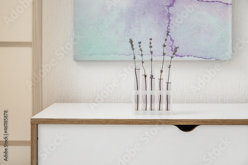 Flasks with beautiful lavender flowers on table in room