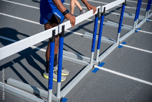 Young man straightened the hurdles lined up on running track